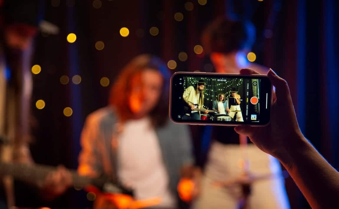 Une personne qui filme des musiciens